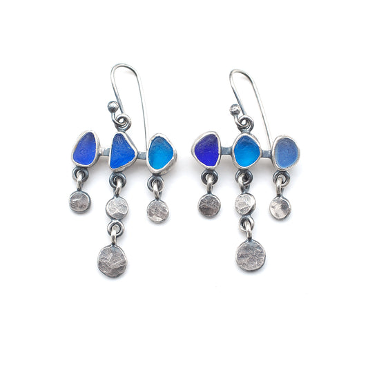 Dot and dangle blue sea glass earrings on a white background.