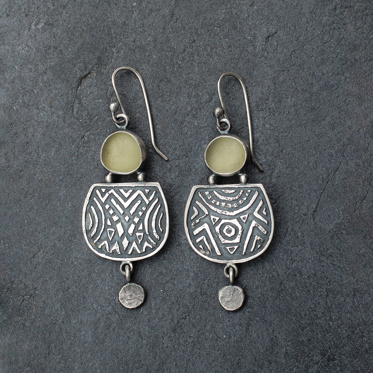 Etched silver earrings with olive green sea glass,  on a slate grey background.