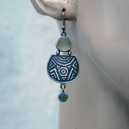 Etched silver earrings with olive green sea glass,  on a mannequin.