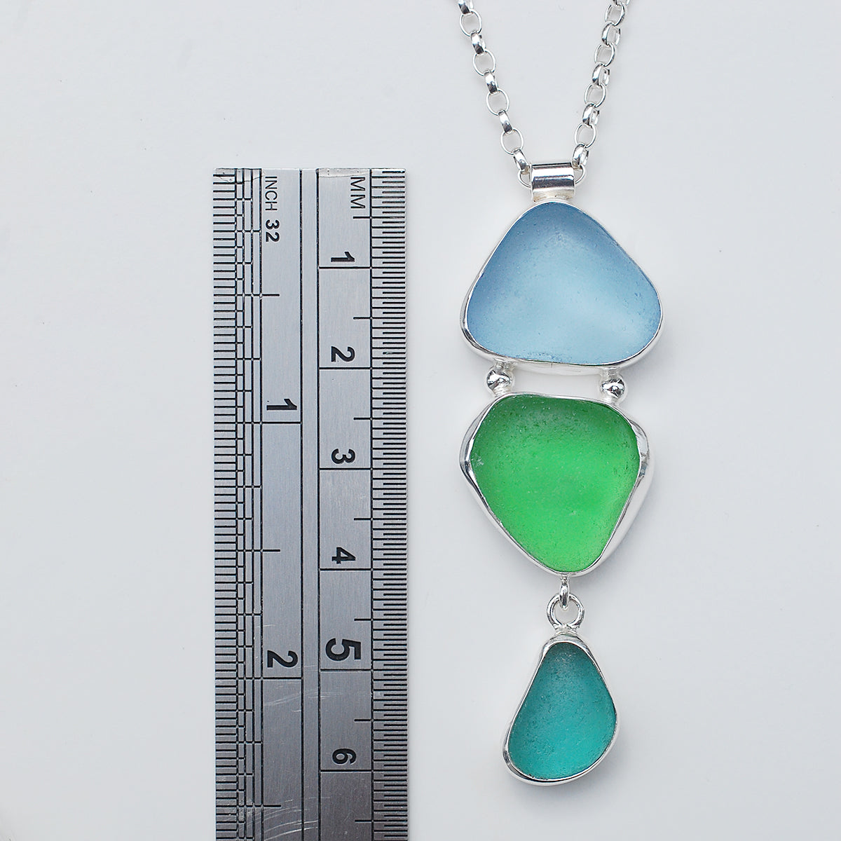 Triple sea glass pendant on a white background, with a ruler