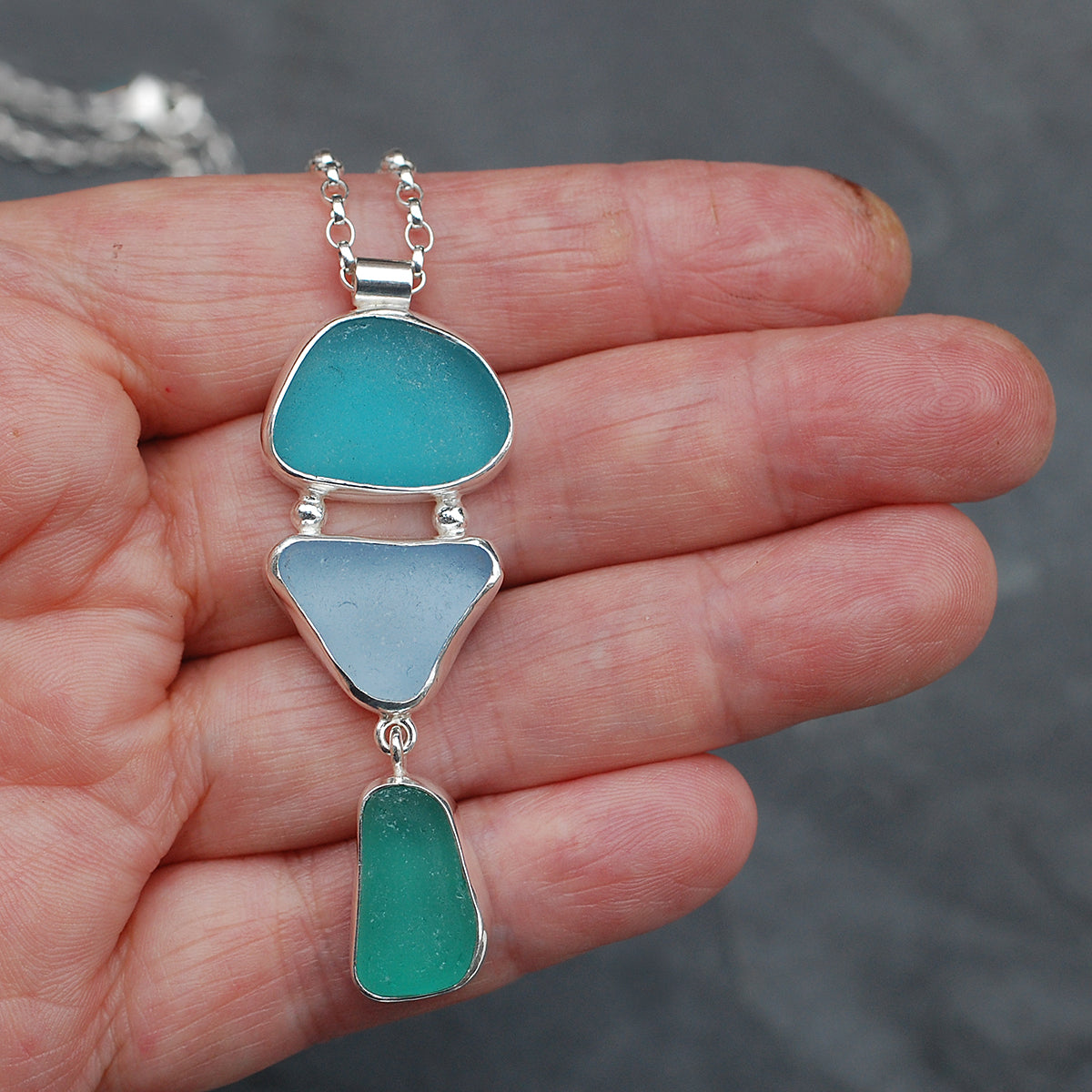 Triple sea glass pendant on a hand